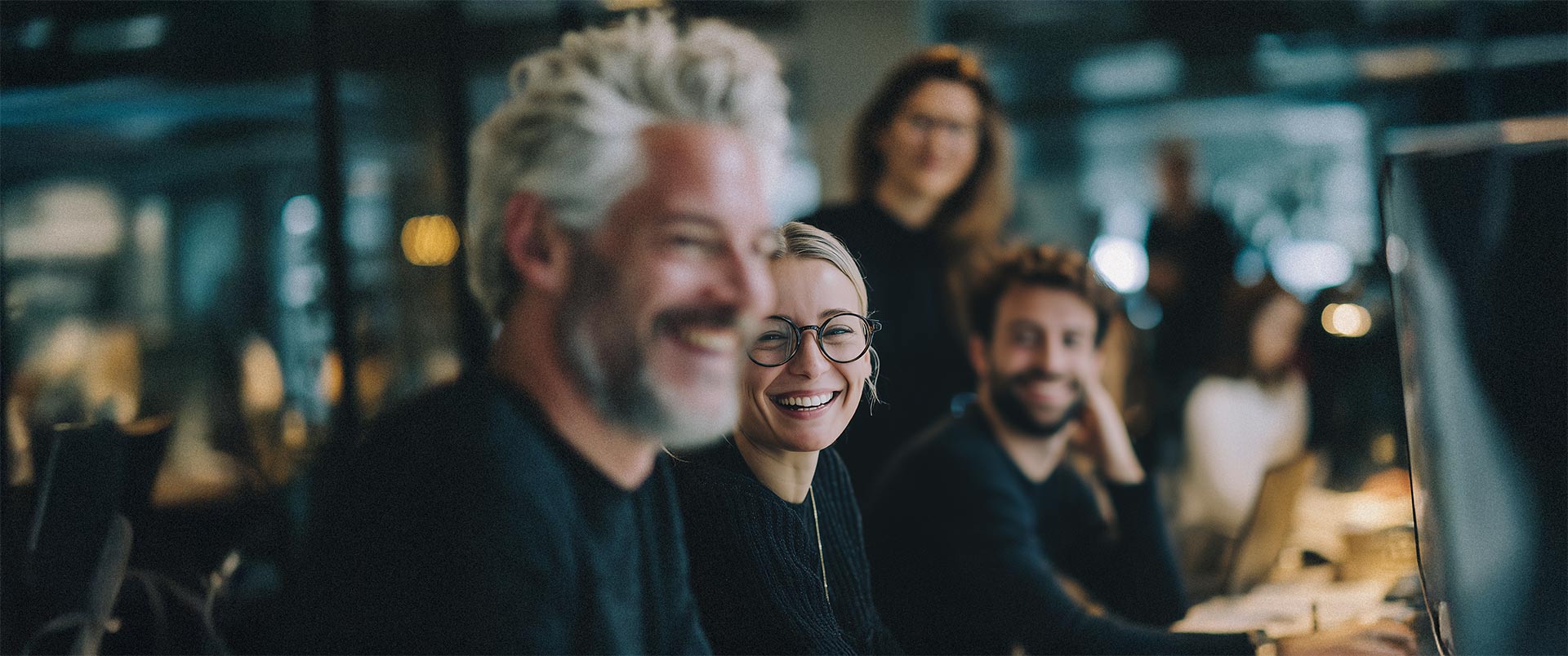 Team in konzentrierter Arbeitsatmosphäre, lachend und im Austausch – Symbol für Zusammenarbeit, Dynamik und Freude an HR Marketing und Recruiting.