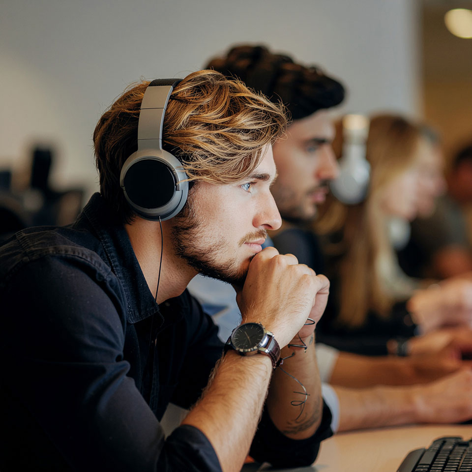 Mitarbeiter mit Kopfhörern konzentriert am Arbeitsplatz – Symbol für Fokus, Professionalität und Engagement im Recruiting und HR Marketing.