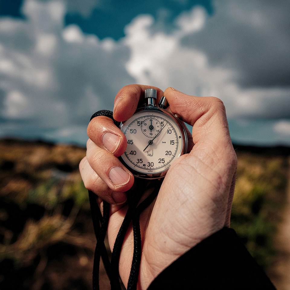 Hand hält Stoppuhr im Sonnenlicht – Symbol für Effizienz und Analyse im Recruiting-Prozess.