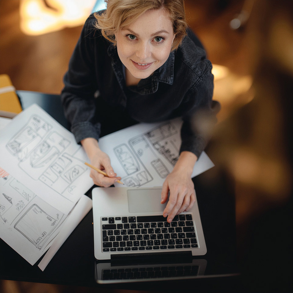 Kreative Person arbeitet mit Laptop und Skizzen an Content-Konzepten – Sinnbild für Ideenreichtum im HR Marketing und Employer Branding.