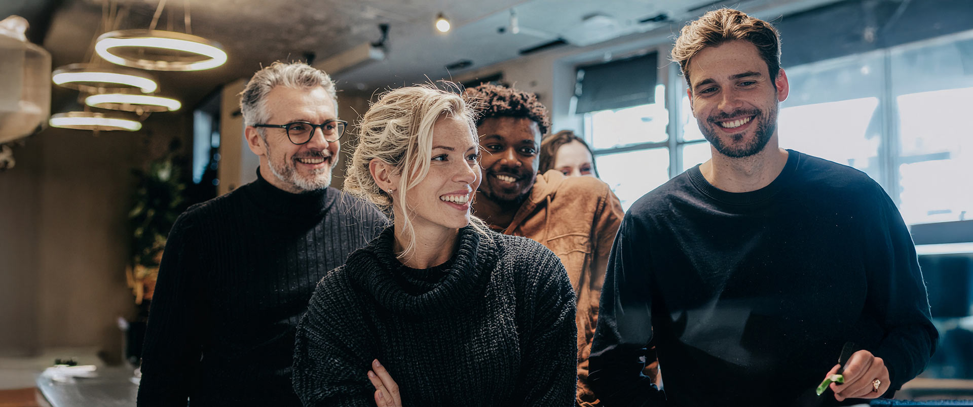 Team in einem modernen Büro, lacht gemeinsam – Sinnbild für Zusammenhalt, Führung und Freude an gemeinsamer Arbeit im HR Marketing und Recruiting.