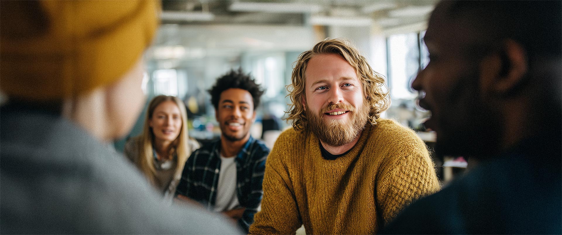 Gruppe von Mitarbeitenden im Gespräch in einem modernen Büro, Symbol für Austausch, Teamarbeit und Zusammenhalt im HR Marketing und Recruiting.