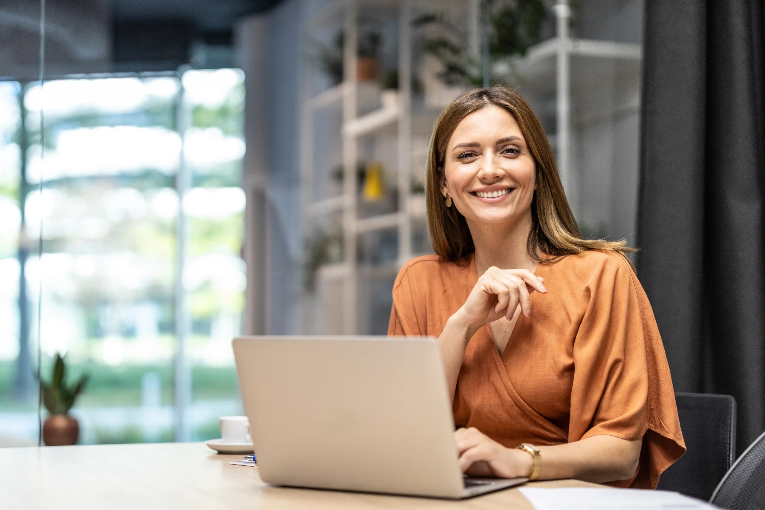Frau am Laptop mit Blick in die Kamera, steht für digitale Contentproduktion.