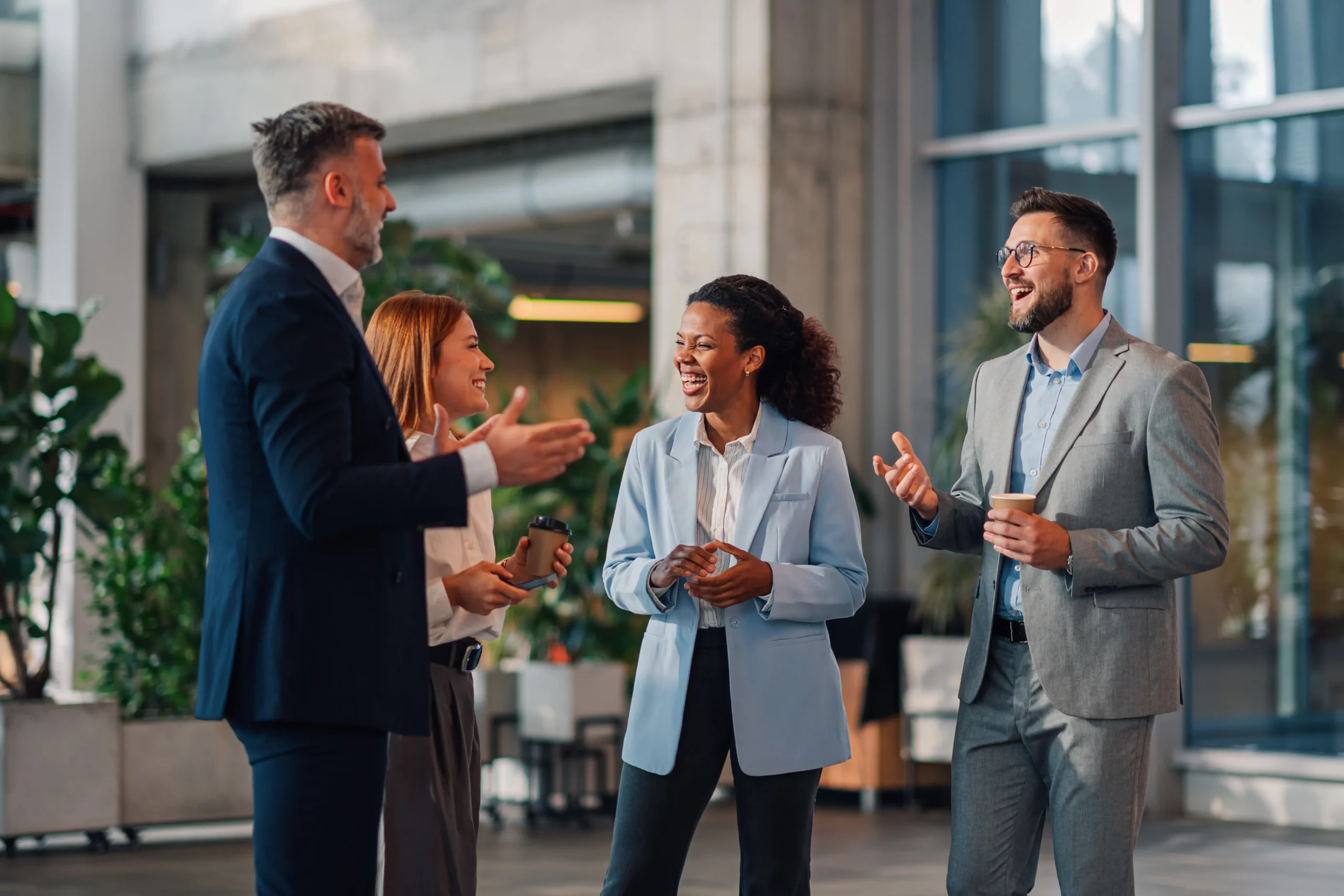 Team in einem modernen Büro, lacht gemeinsam – Sinnbild für Zusammenhalt, Führung und Freude an gemeinsamer Arbeit im HR Marketing und Recruiting.